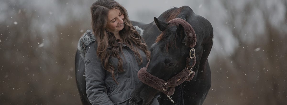 pferd und frau stehen nebeneinander im schnee