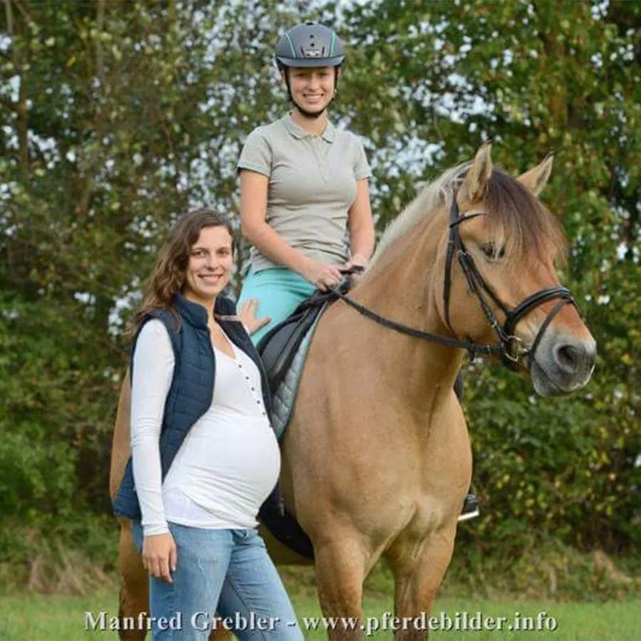 Schwangere Frau neben Pferd mit Reiterin auf dem Pferd Schwangere Frau neben Pferd mit Reiterin auf dem Pferd